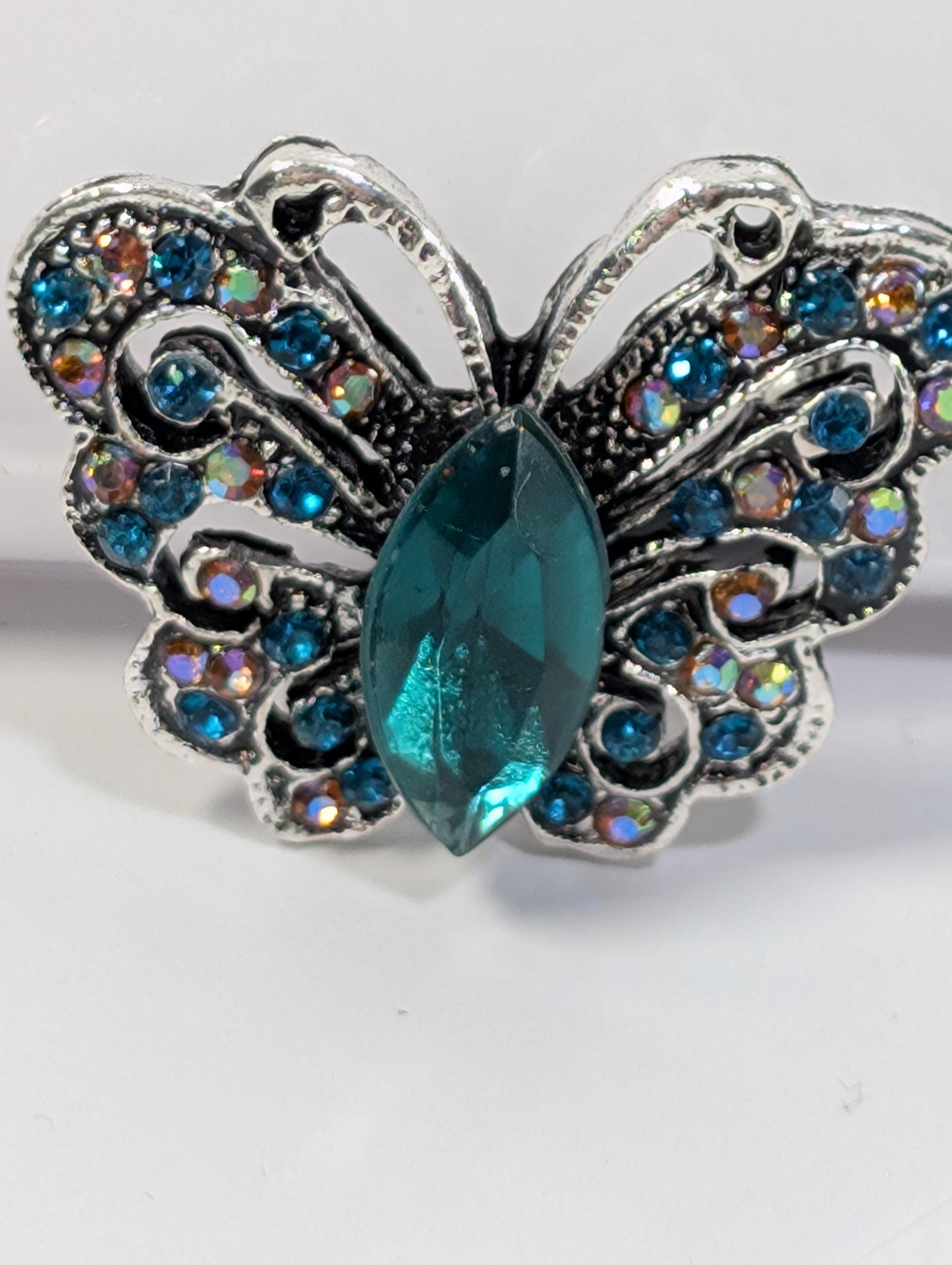 A silver butterfly-shaped ring with a large blue gemstone in the center.