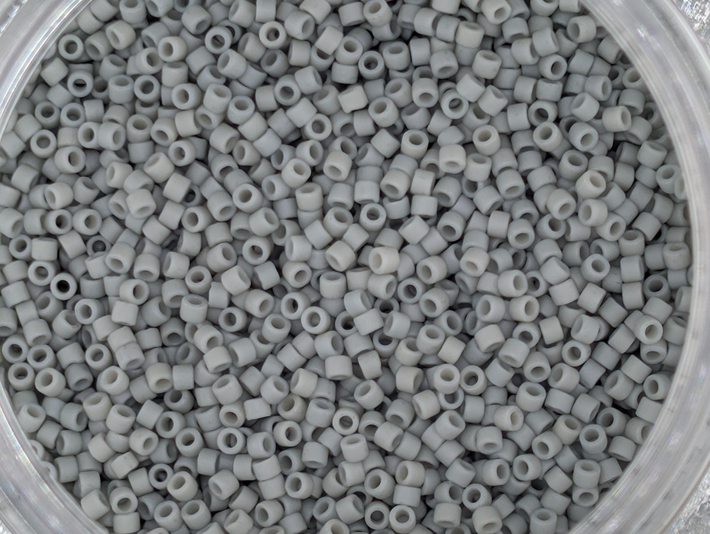 A close-up image of a container filled with small, white beads or plastic beads.