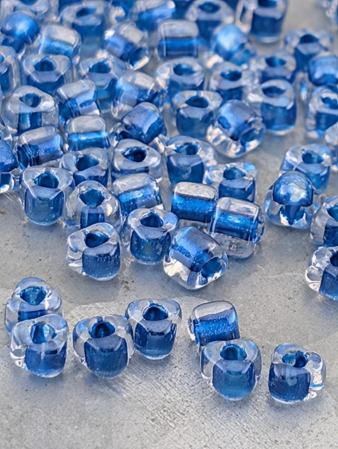 a collection of clear glass beads in various shades of blue, scattered across a surface.