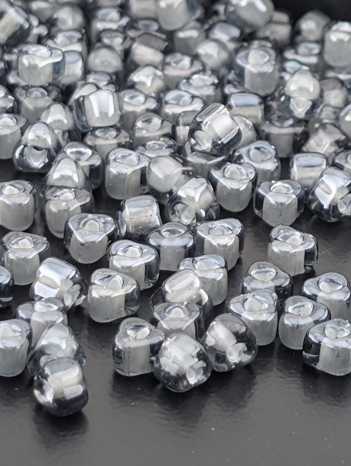 a collection of small, clear glass beads scattered across a dark surface.
