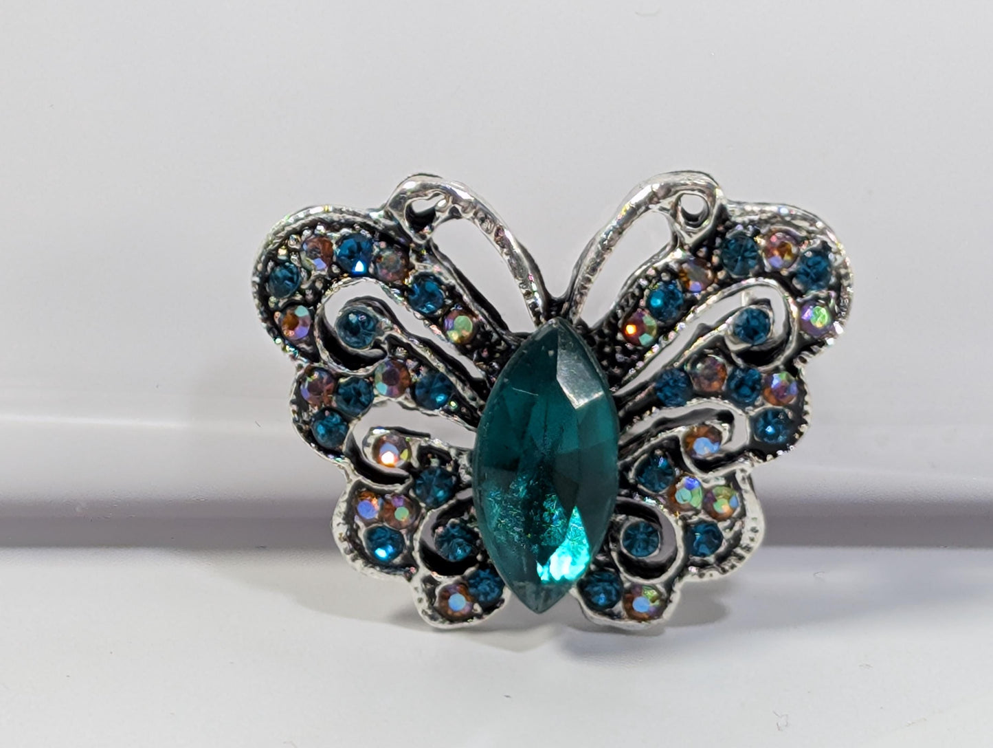 A silver butterfly-shaped pendant with a large blue gemstone in the center.