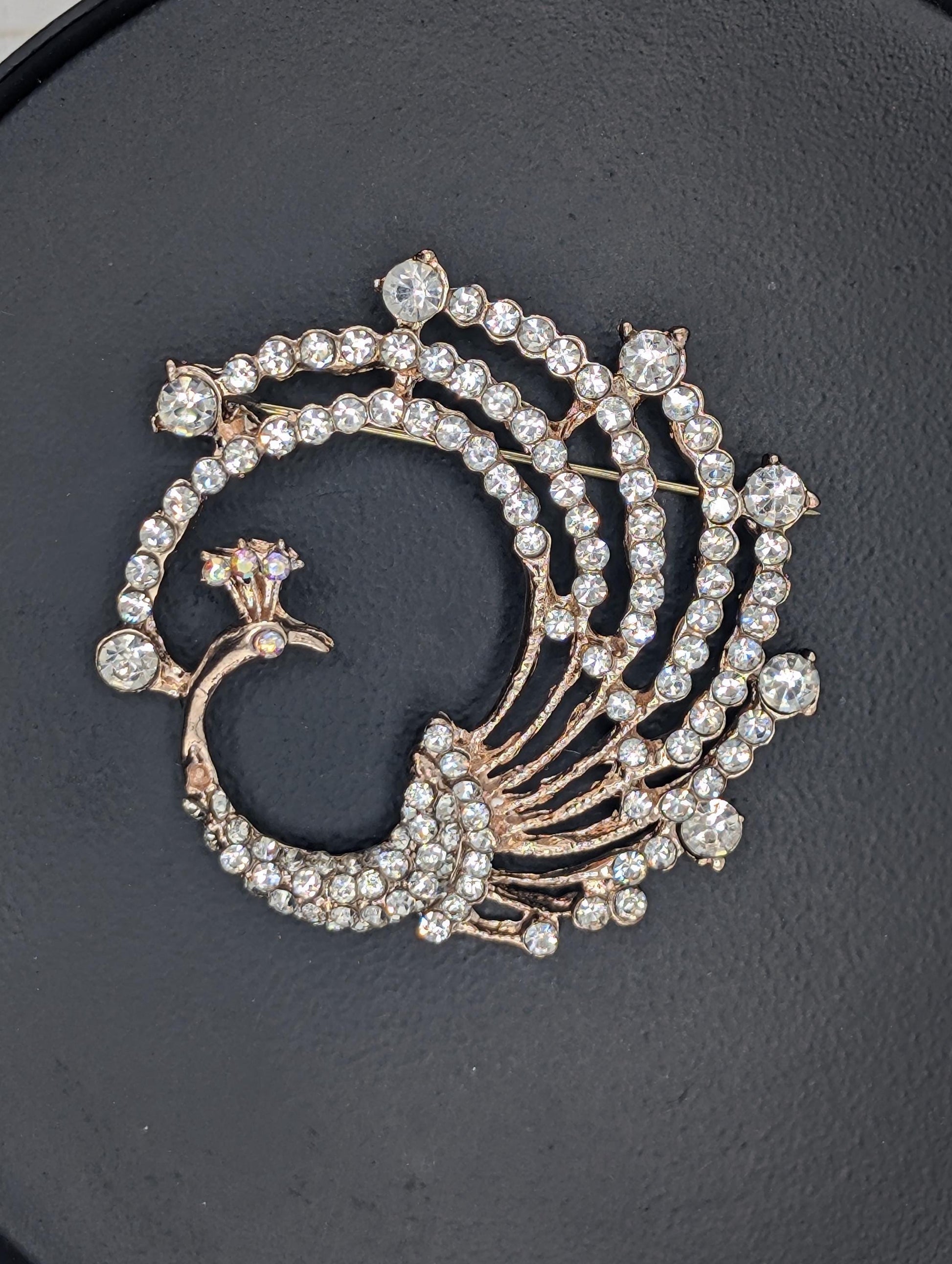 A decorative brooch with a swirling design of sparkling diamonds and a floral motif.