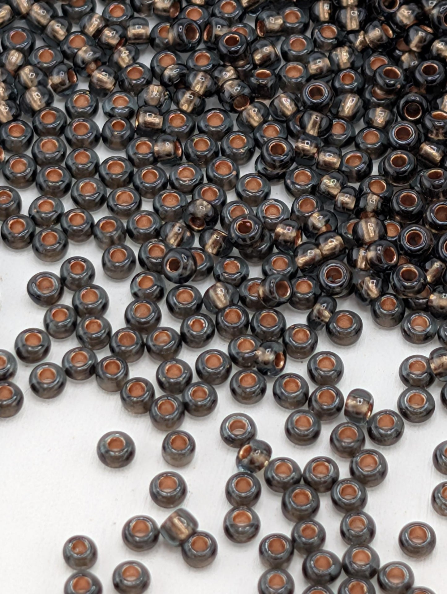 a large number of small, round beads in various shades of black and brown, scattered across a white surface.