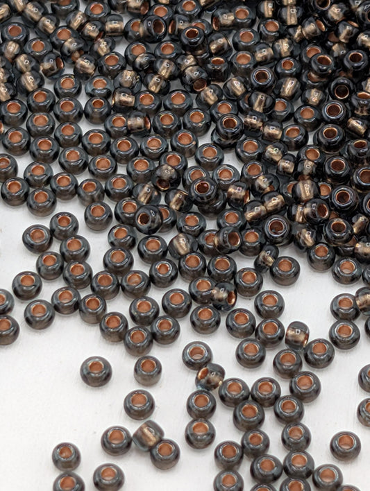 a large number of small, round beads in various shades of black and brown, scattered across a white surface.