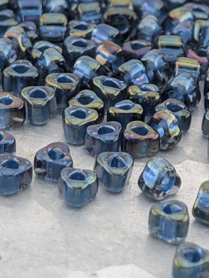 a collection of small, blue glass beads scattered on a surface.