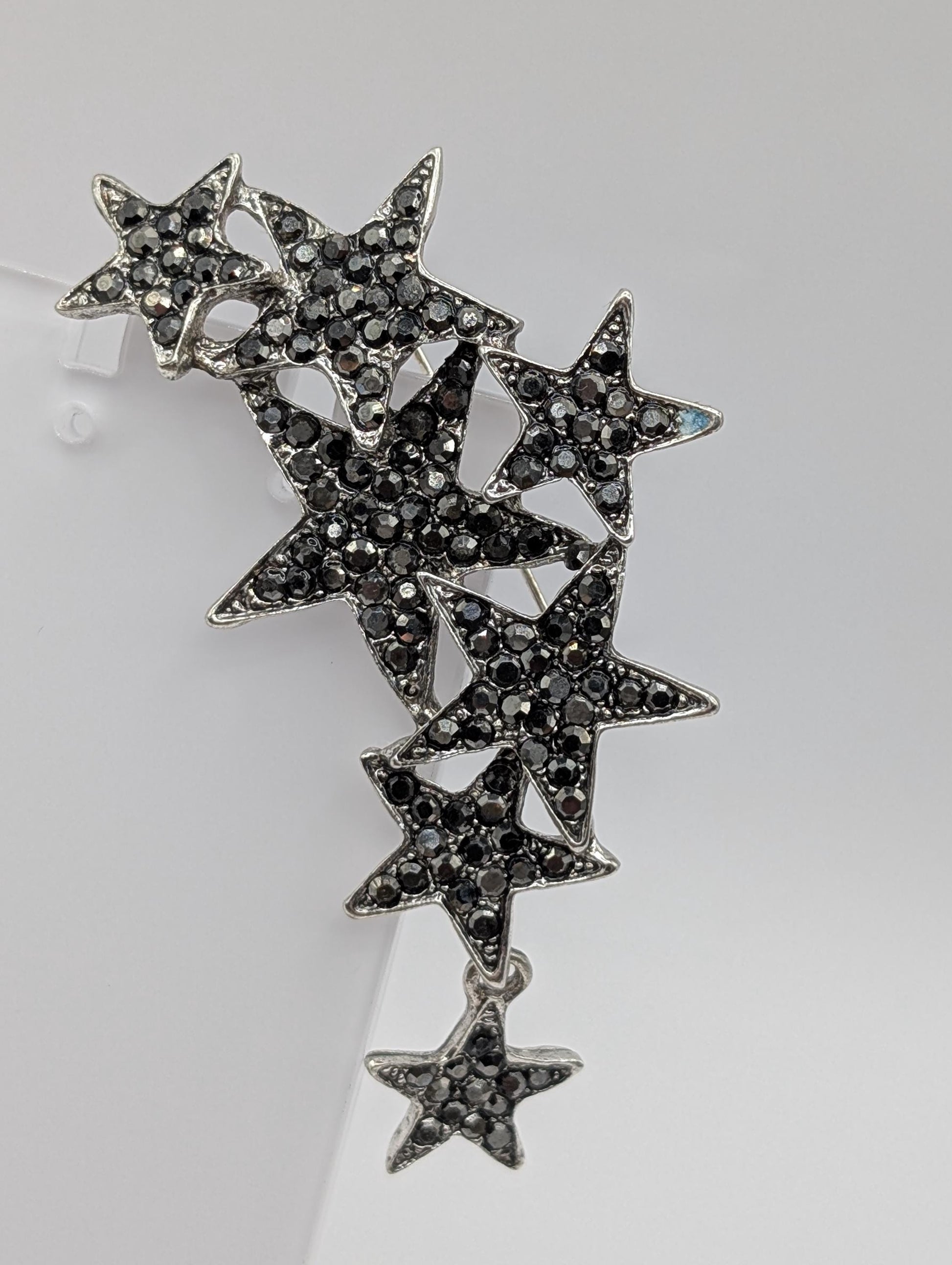 A silver brooch with black diamond-like stones arranged in a star-like pattern.