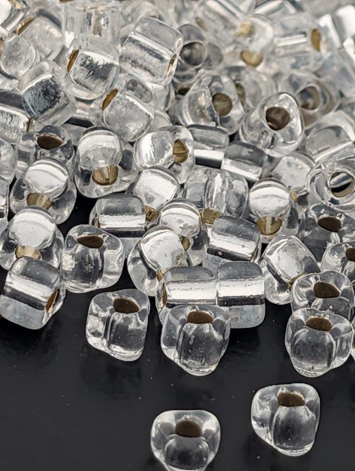 a collection of clear glass beads scattered on a dark surface.