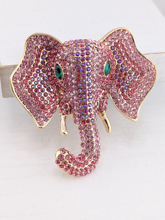 A decorative elephant head brooch made of pink and purple rhinestones, with gold accents.