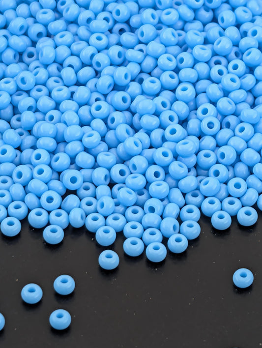 a large pile of small, round blue beads scattered on a dark surface.