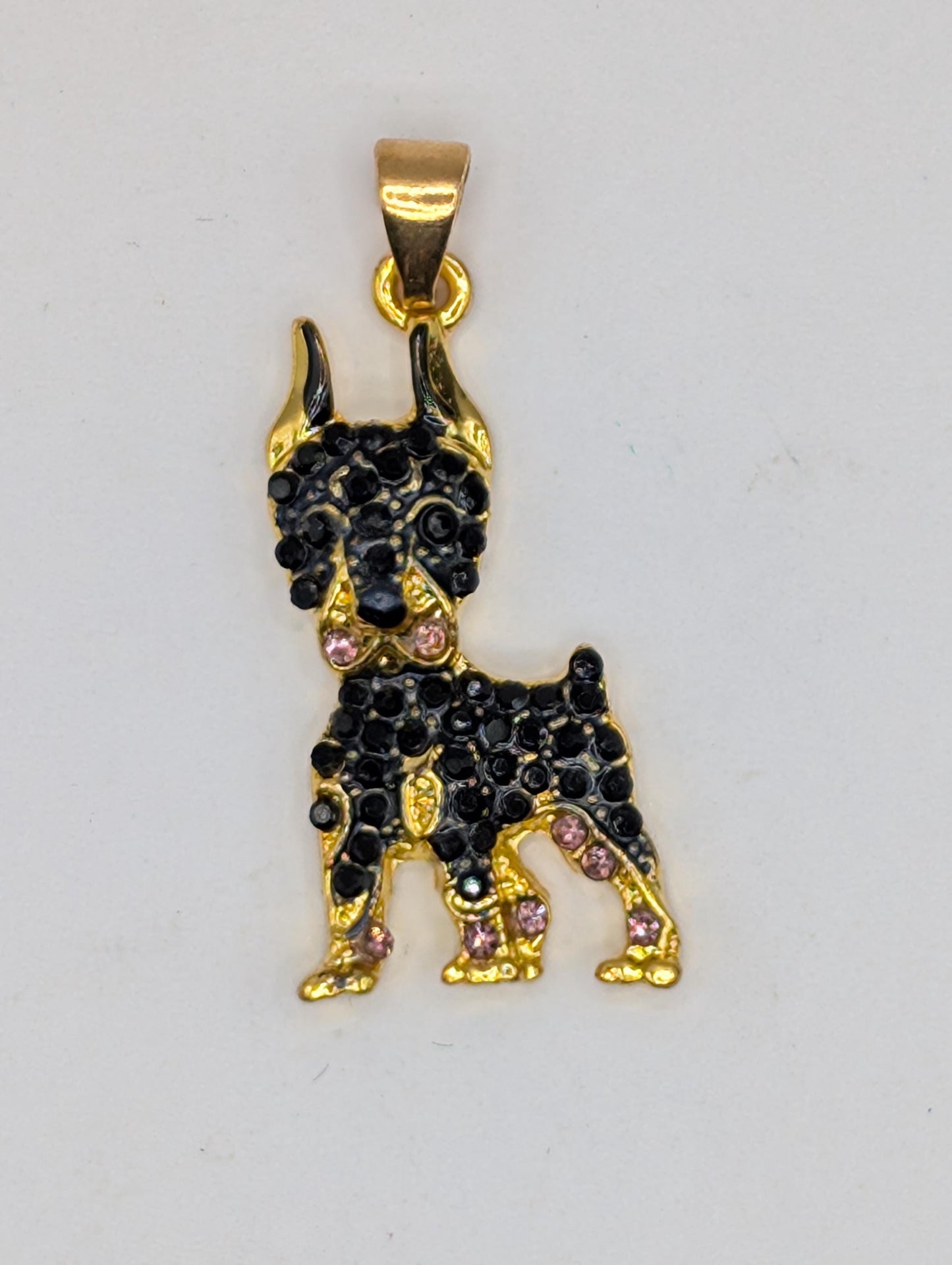 A gold-colored pendant in the shape of a dog, adorned with black gemstones.