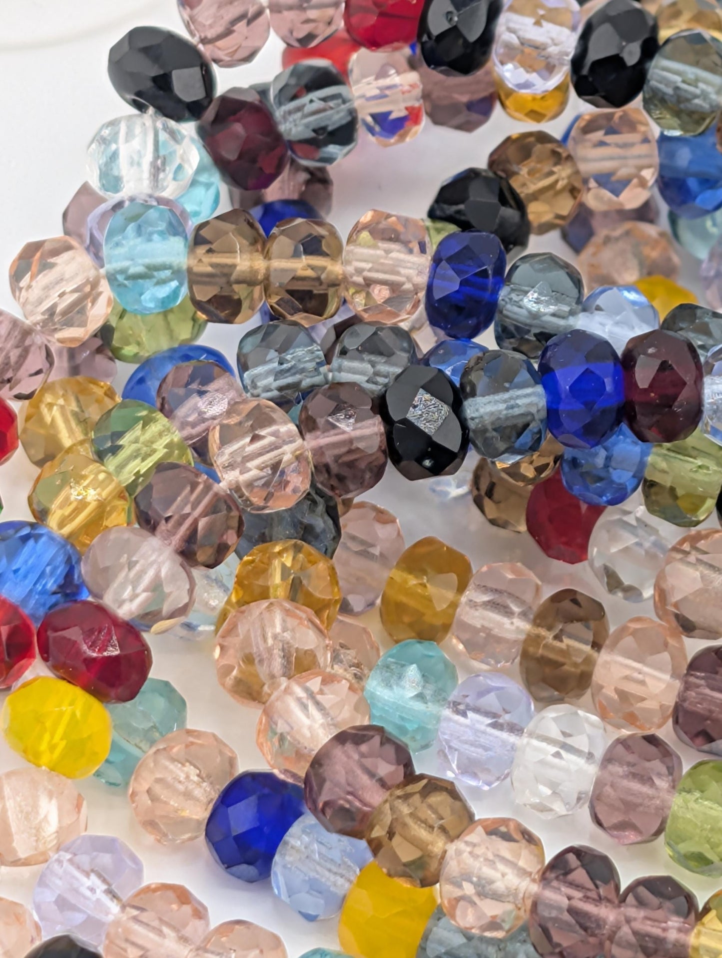 The image is a close-up of a collection of colorful glass beads, including clear, blue, and multicolored glass beads, arranged in a visually appealing manner.