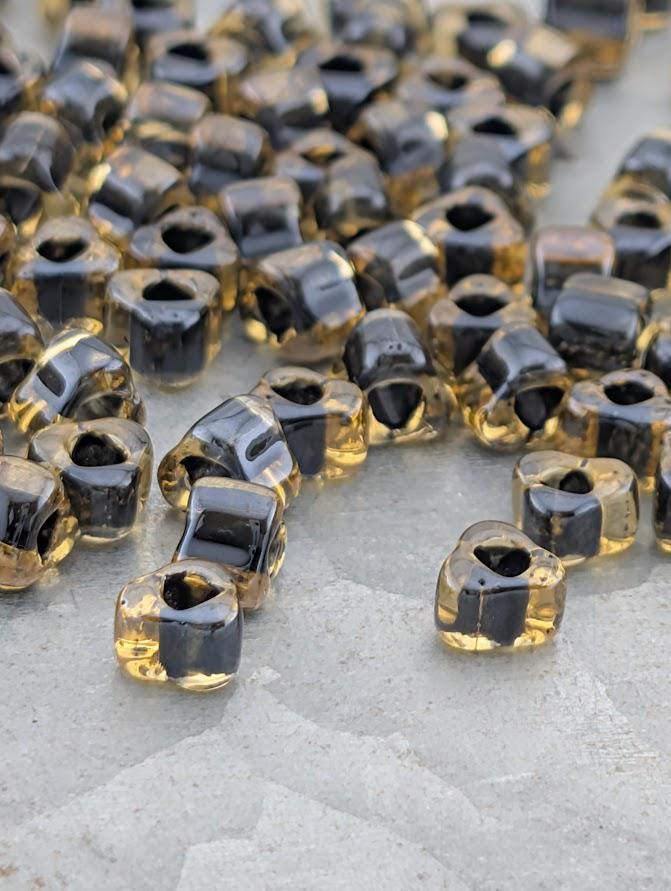 a collection of small, clear glass beads in various shades of yellow and black, scattered on a surface.