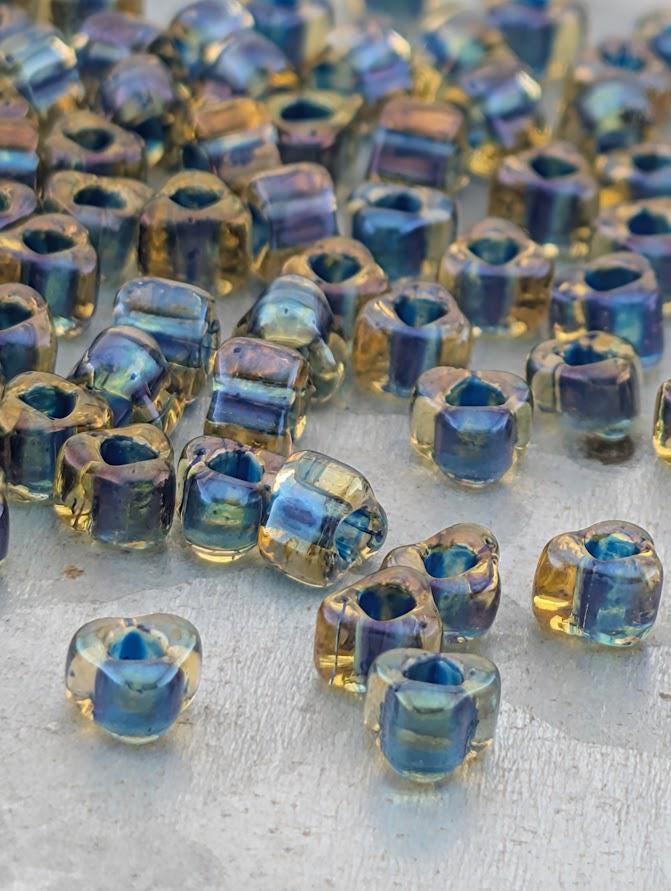 a collection of small, clear glass beads in various colors, including blue, yellow, and orange, scattered on a surface.
