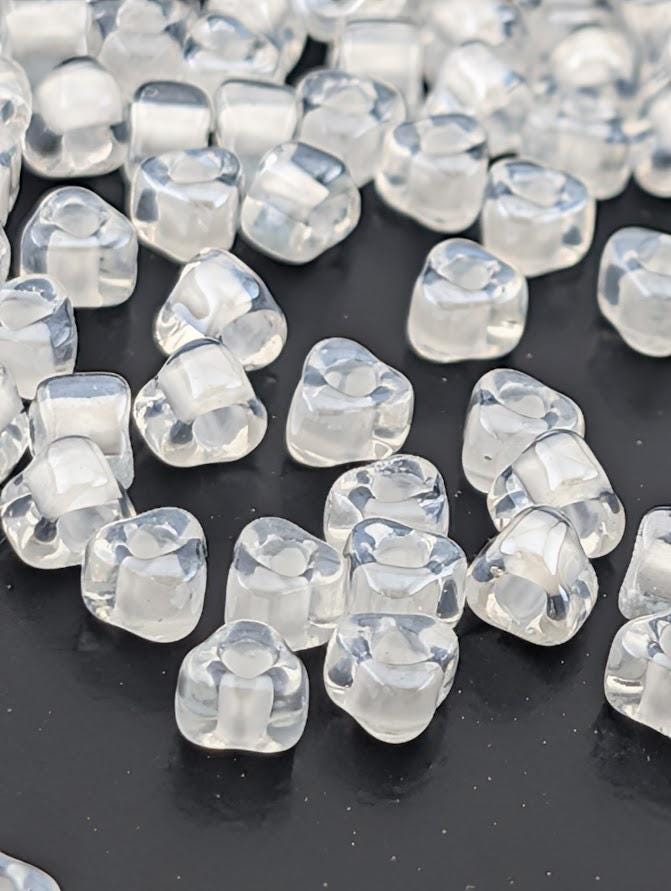 a collection of clear, transparent beads scattered across a dark background.