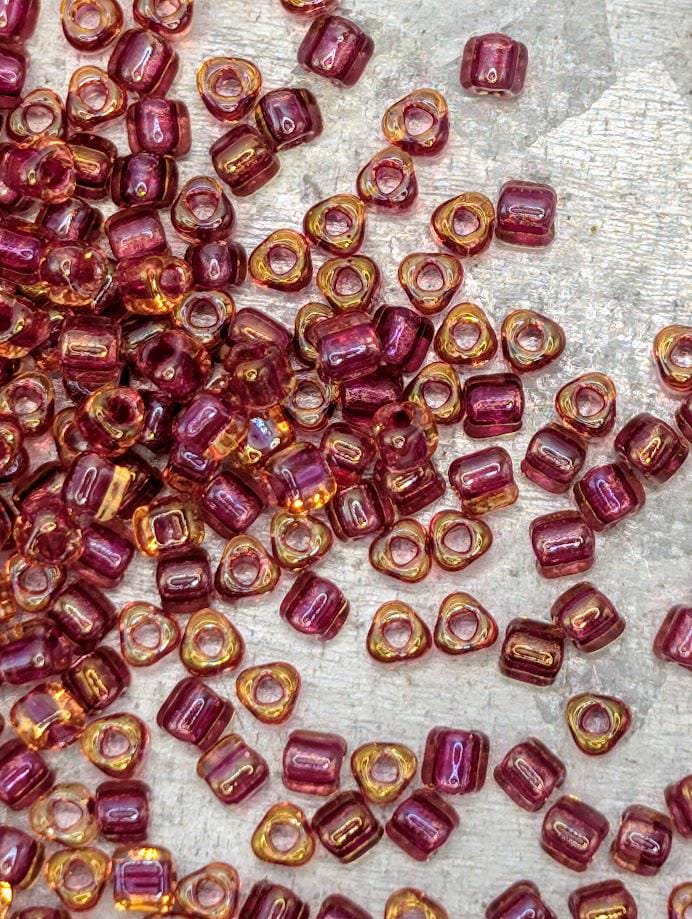a collection of small, colorful beads scattered across a surface, with a variety of colors including shades of pink, orange, and yellow.