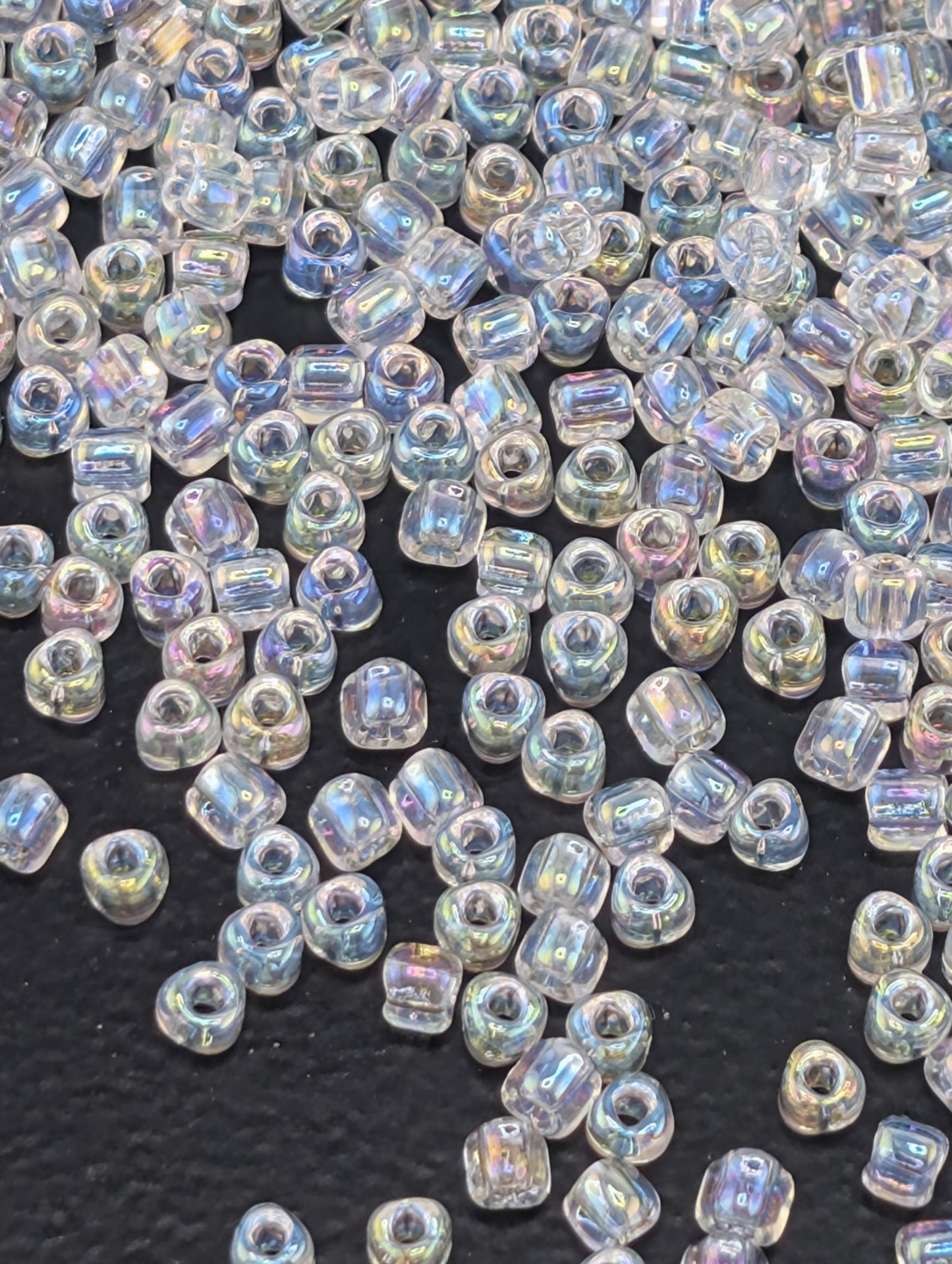a collection of clear, iridescent beads scattered across a dark surface.