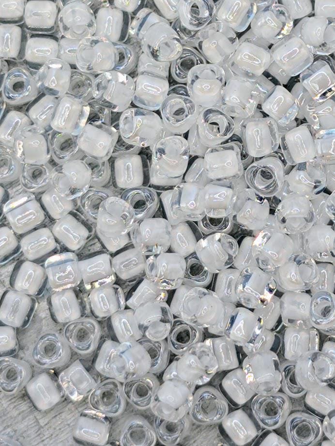 The image is a close-up of numerous clear glass beads scattered across a surface.