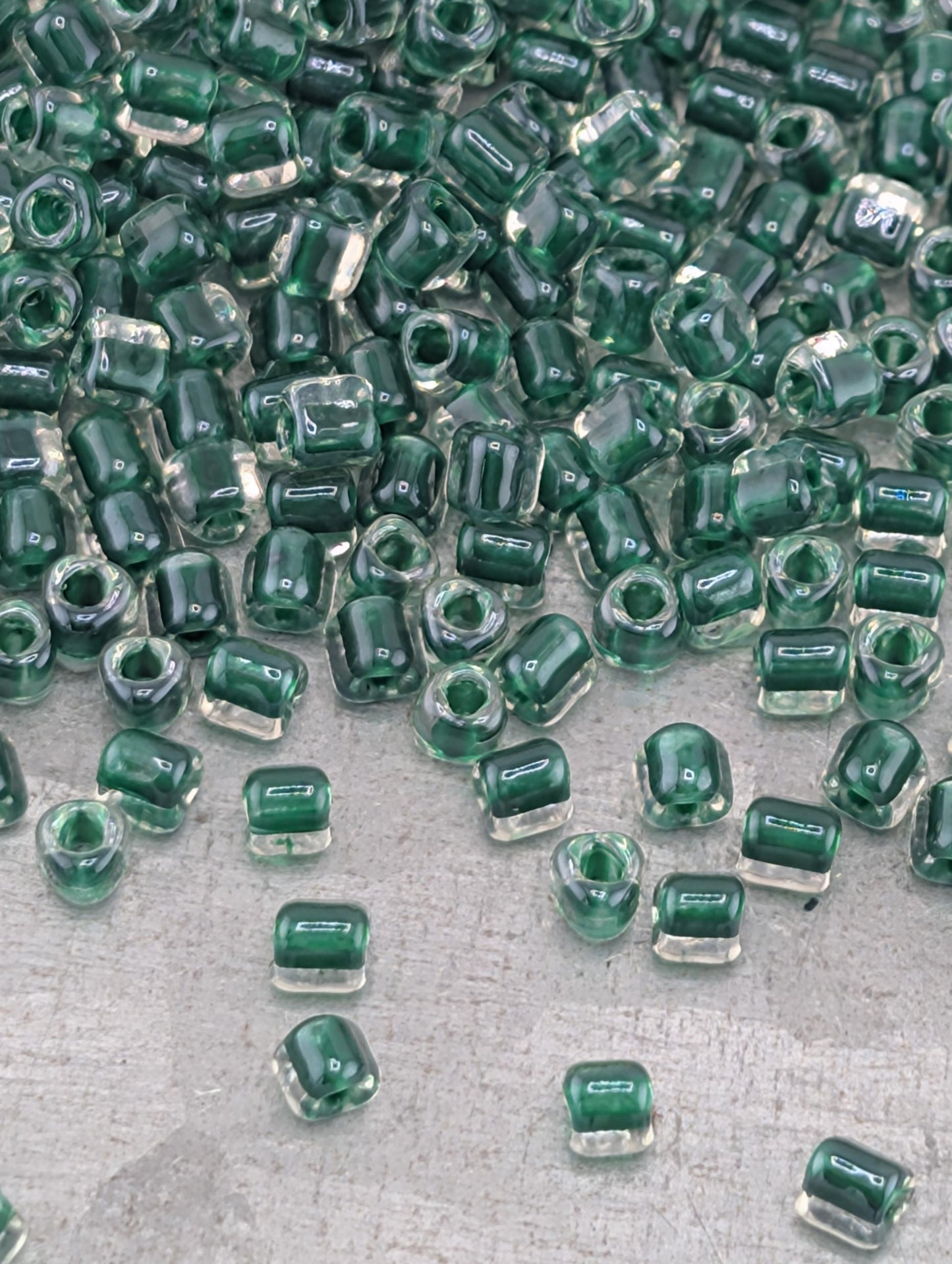 a collection of green glass beads scattered on a surface, with some of the beads overlapping each other.
