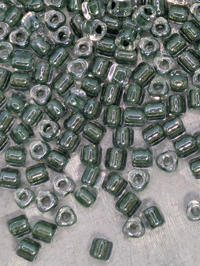 a collection of green glass beads scattered on a surface, with some of the beads overlapping each other.