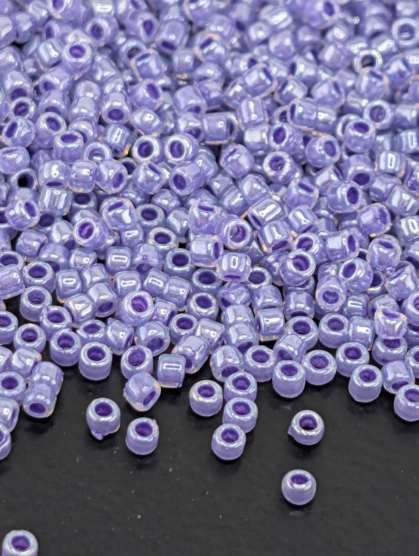 a large number of small, round beads in various shades of purple, scattered across a dark surface.