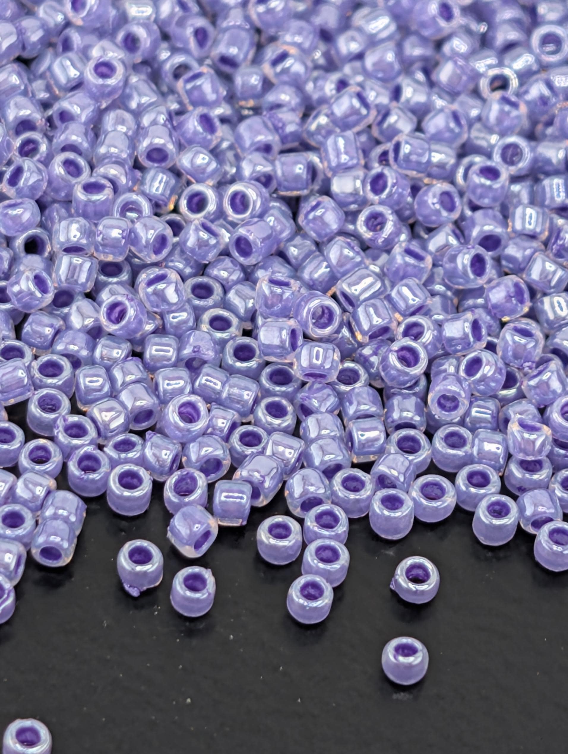 a large number of small, round beads in various shades of purple, scattered across a dark surface.