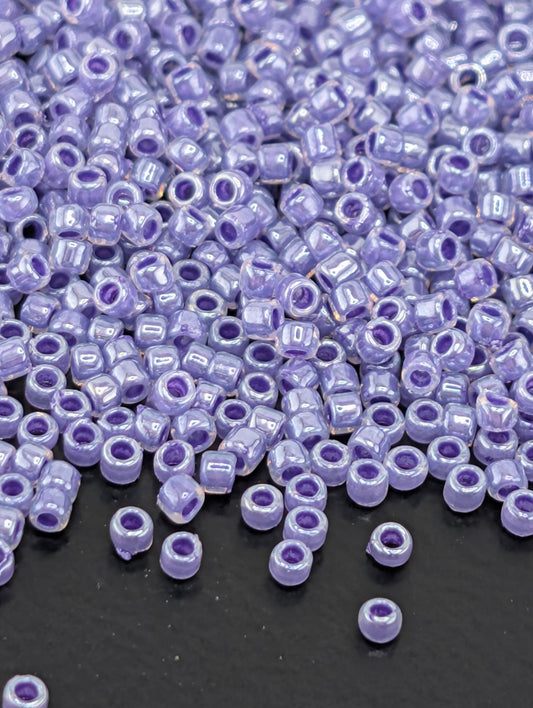 a large number of small, round beads in various shades of purple, scattered across a dark surface.