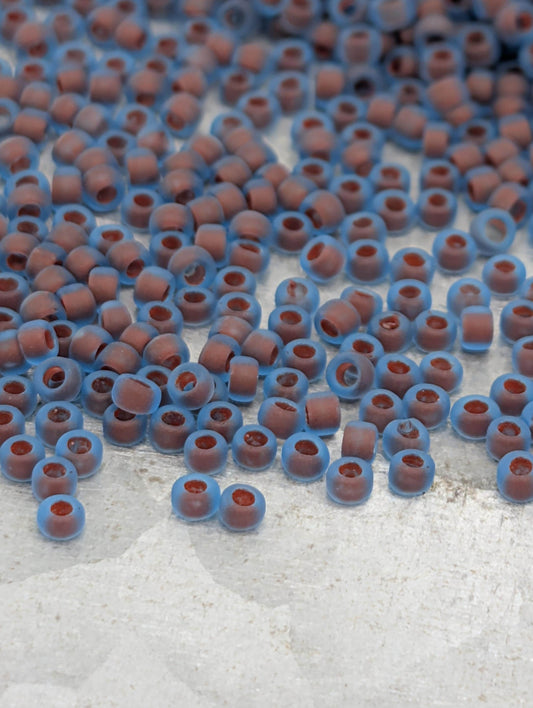 a collection of small, round beads in shades of blue and brown, scattered across a white surface.