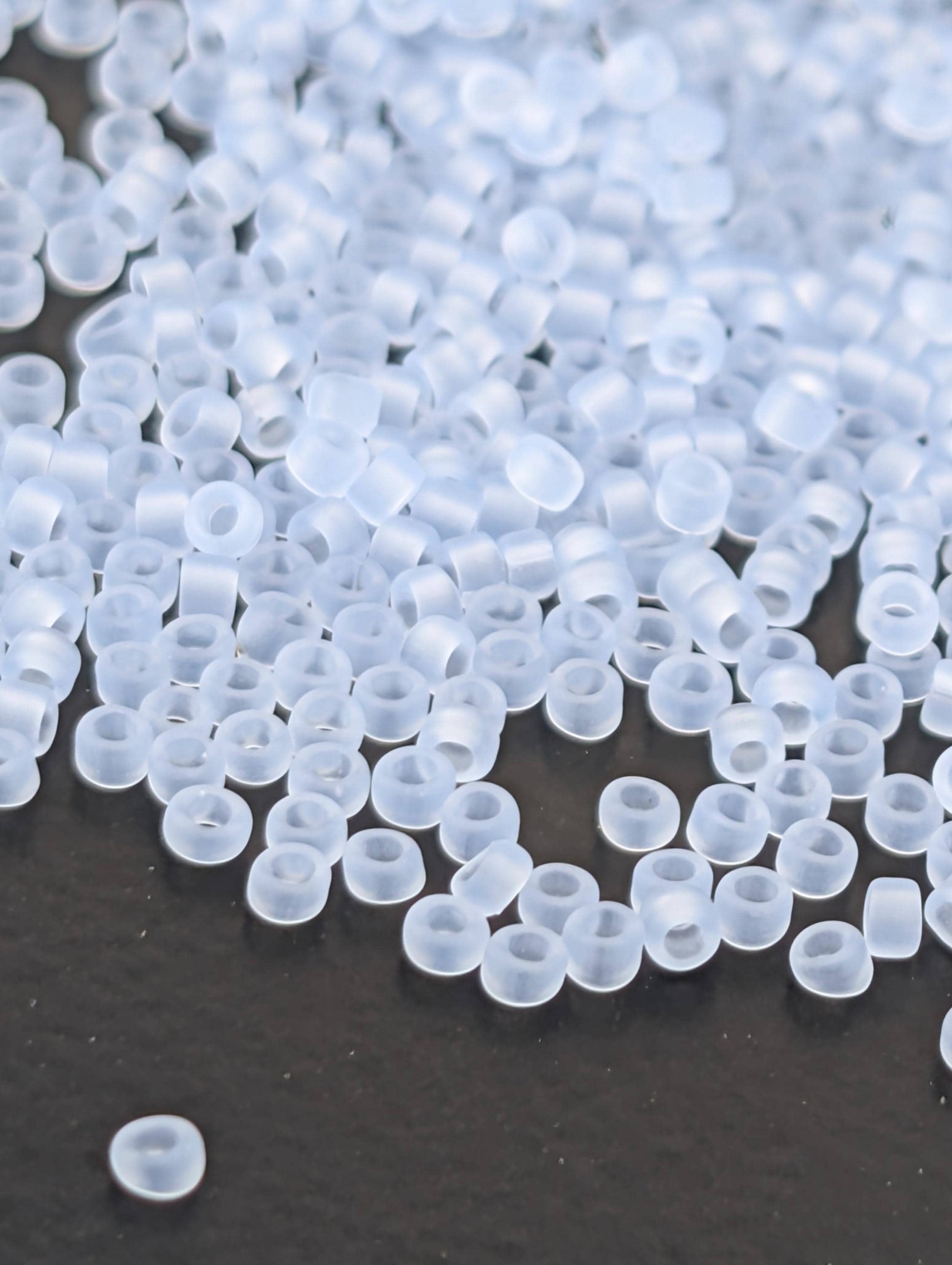 a close-up view of numerous transparent, clear beads scattered across a dark surface.