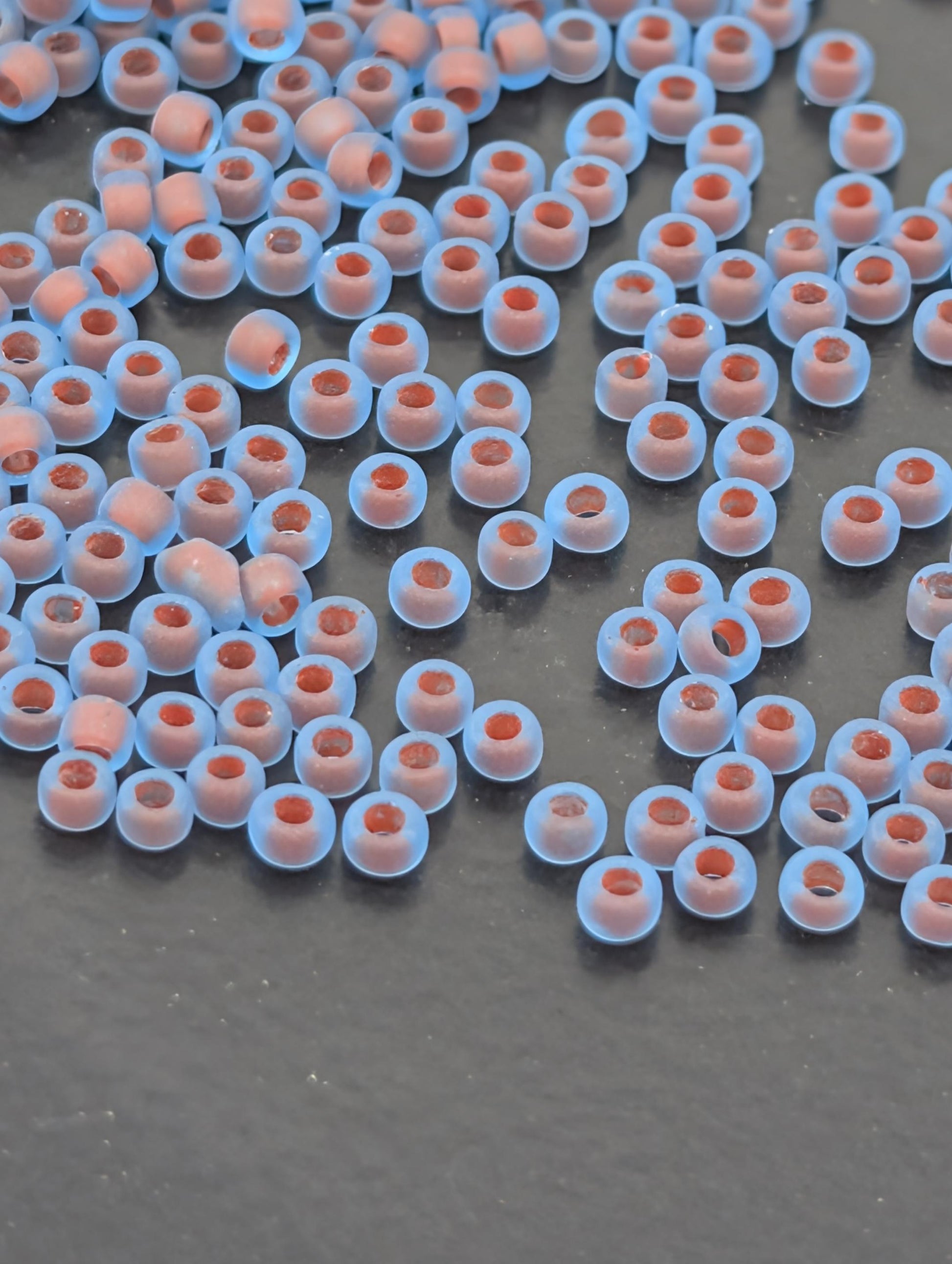 a collection of small, round, blue beads scattered across a dark surface.