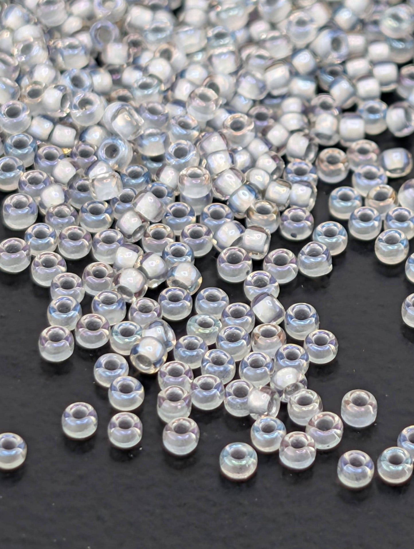 a collection of clear, transparent beads scattered on a dark surface.