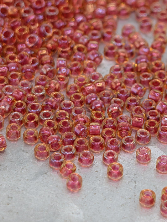 a close-up view of numerous small, clear beads in shades of pink and orange, scattered across a surface.