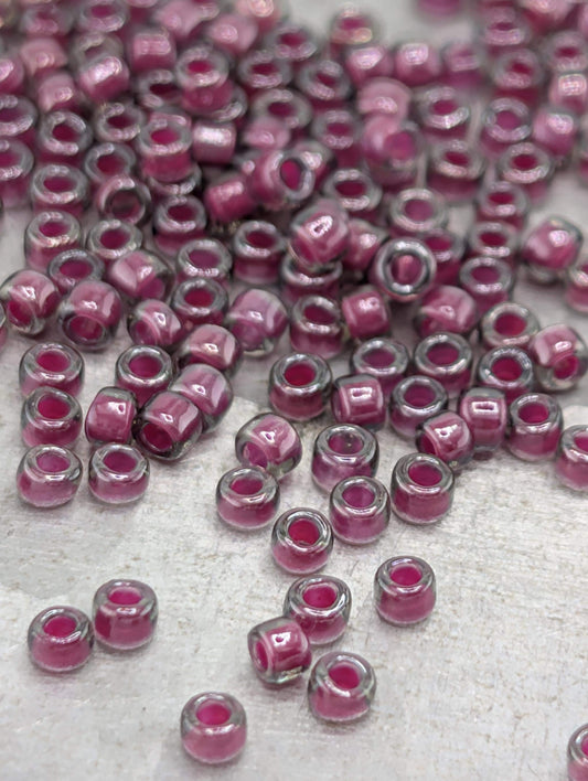 a collection of small, clear beads in shades of pink and purple, scattered across a surface.