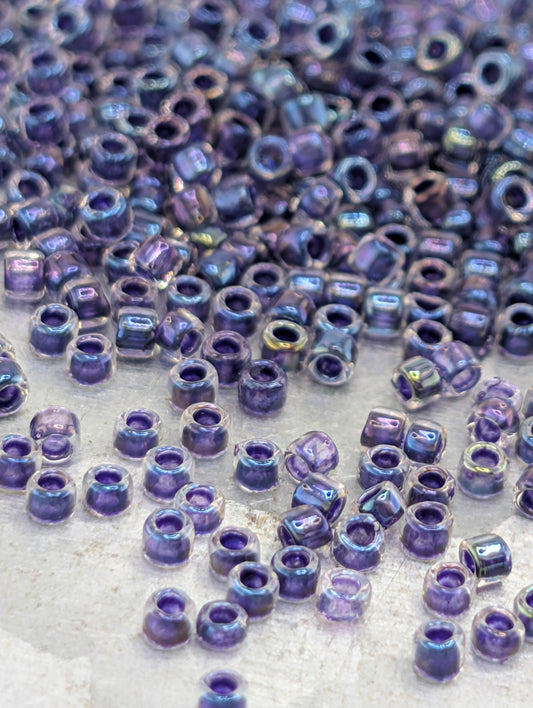a close-up view of numerous small, clear beads in various shades of purple, scattered across a surface.