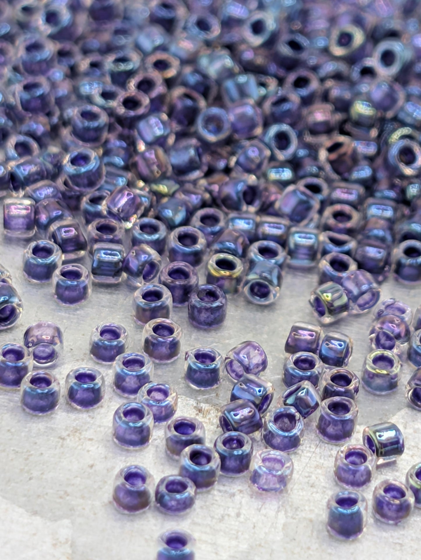 a close-up view of numerous small, clear beads in various shades of purple, scattered across a surface.