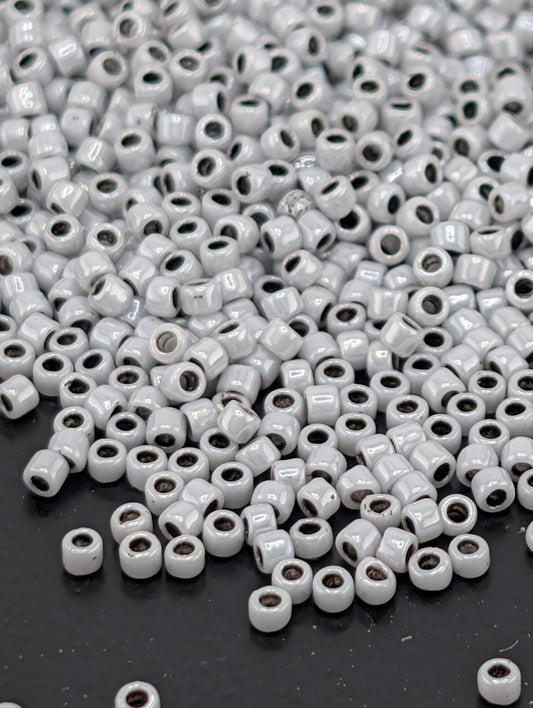 a large pile of small, white beads scattered on a dark surface.
