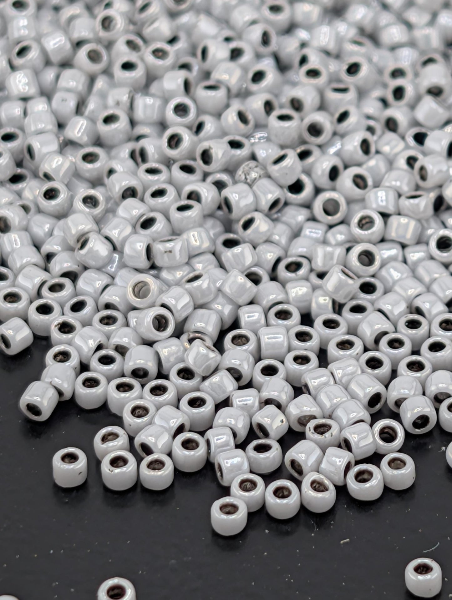a large pile of small, white beads scattered on a dark surface.