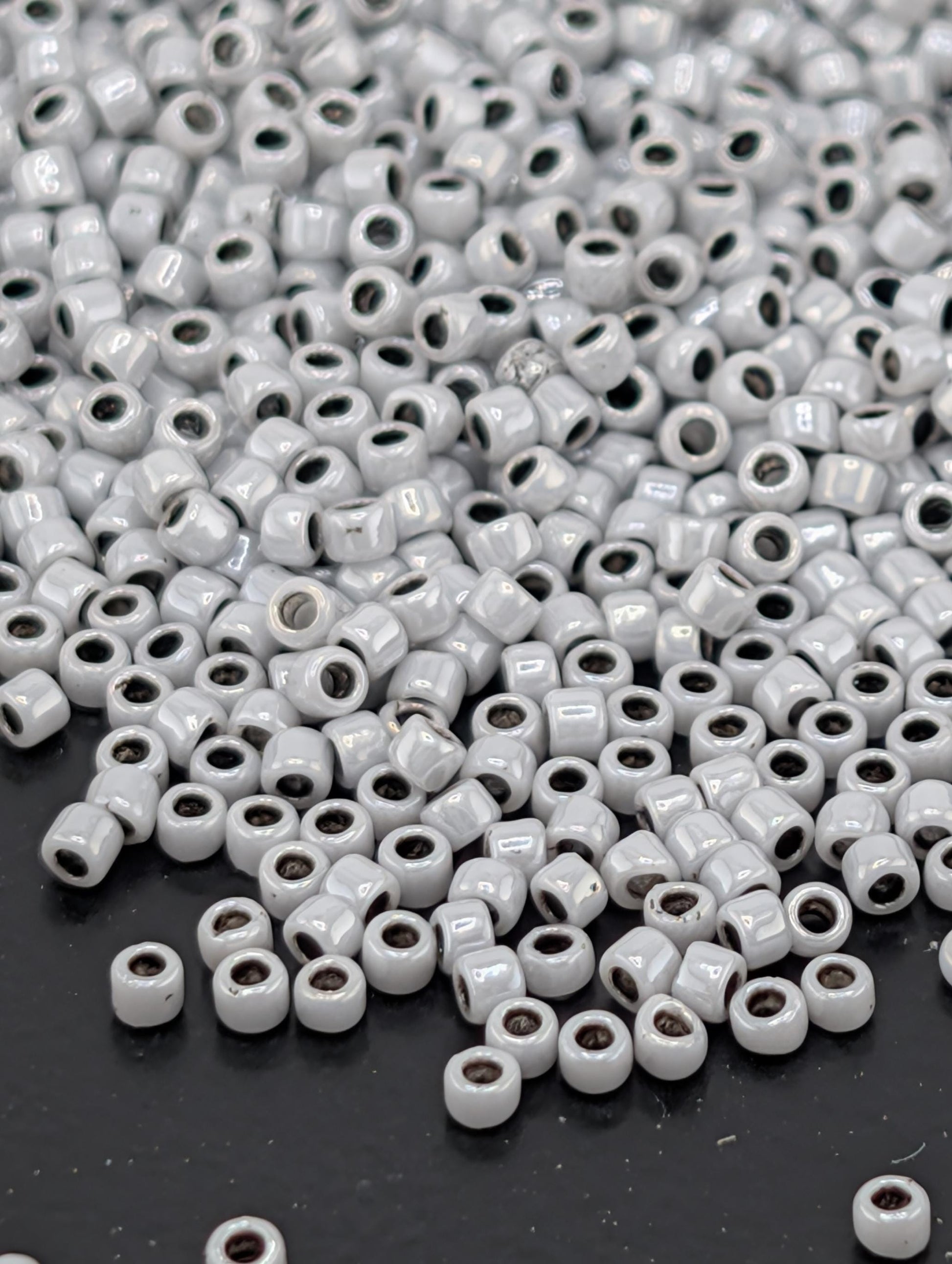 a large pile of small, white beads scattered on a dark surface.