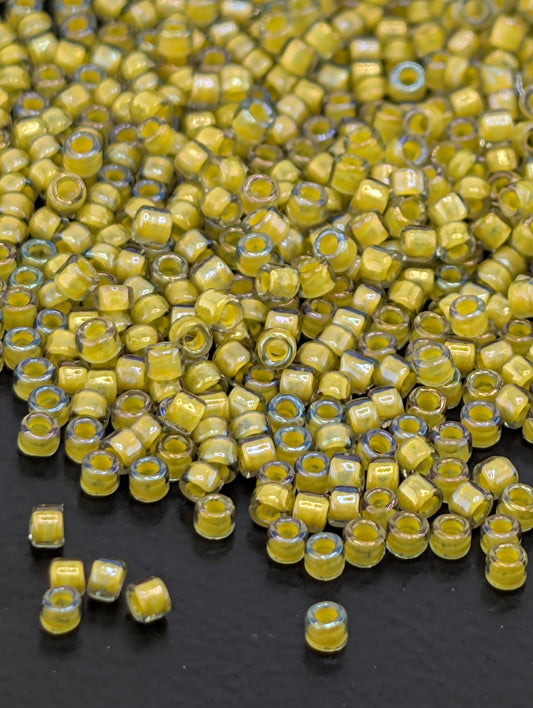 a large pile of small, yellow beads scattered on a dark surface.