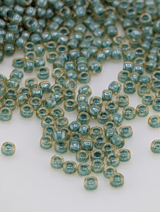 a collection of small, clear beads in various shades of blue and yellow, scattered across a white surface.