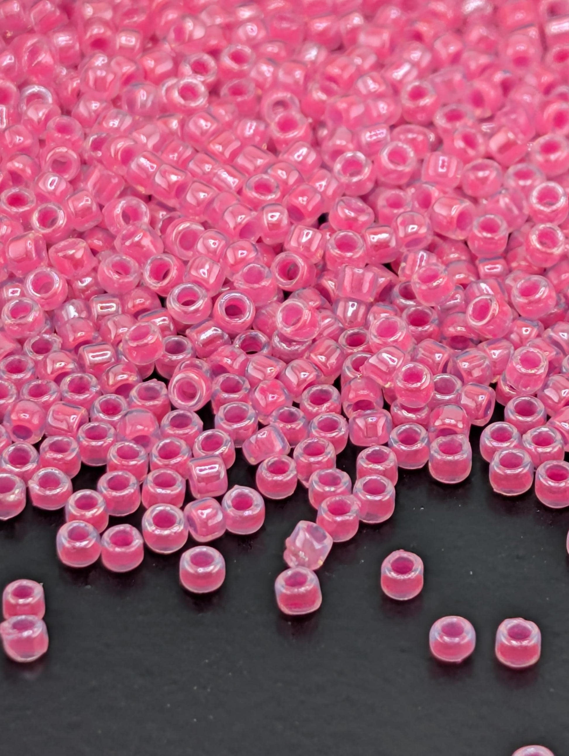 a close-up view of numerous small, clear beads in a vibrant shade of pink, scattered across a dark background.