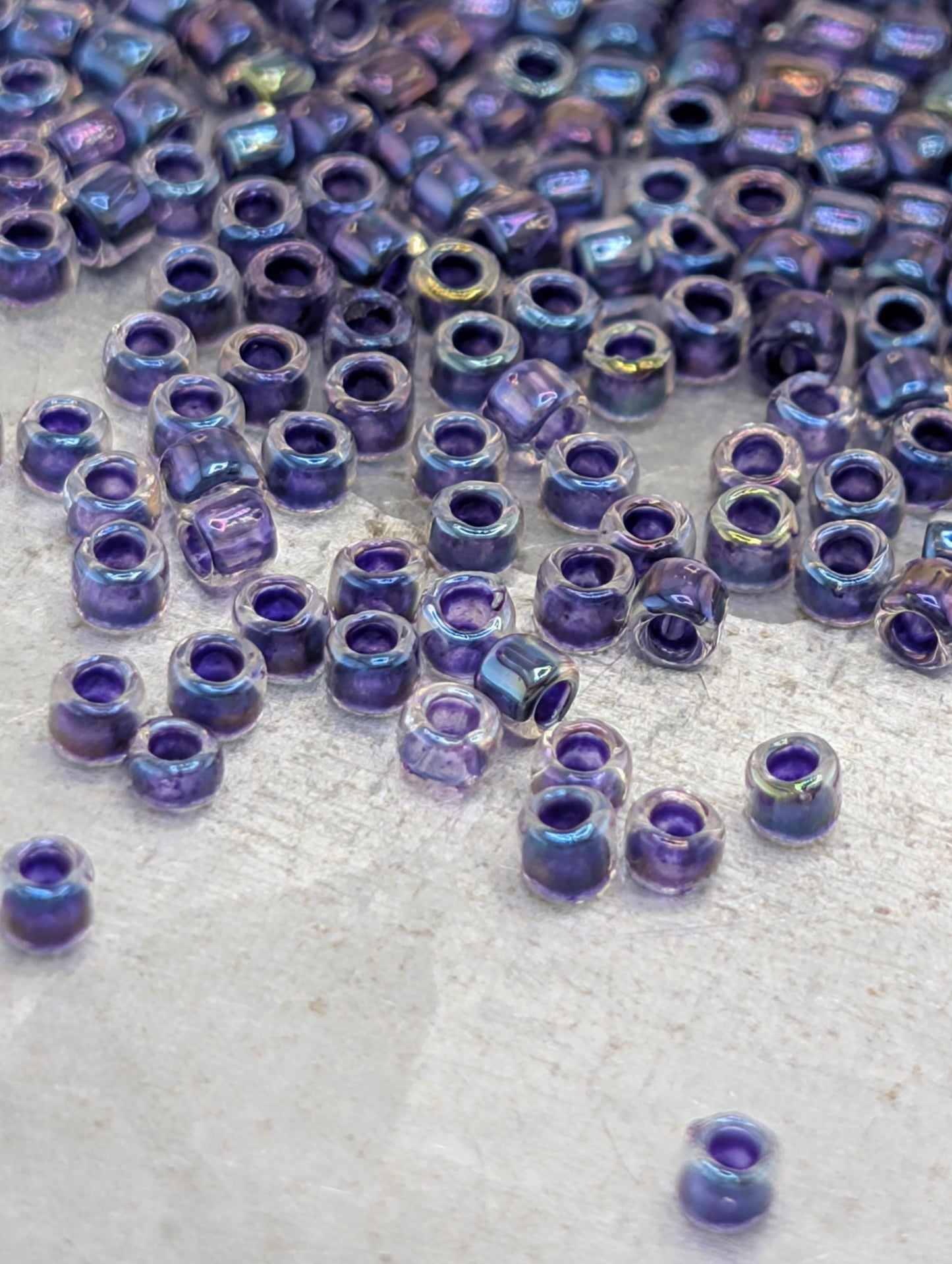 a collection of small, clear beads in various shades of purple scattered across a surface.