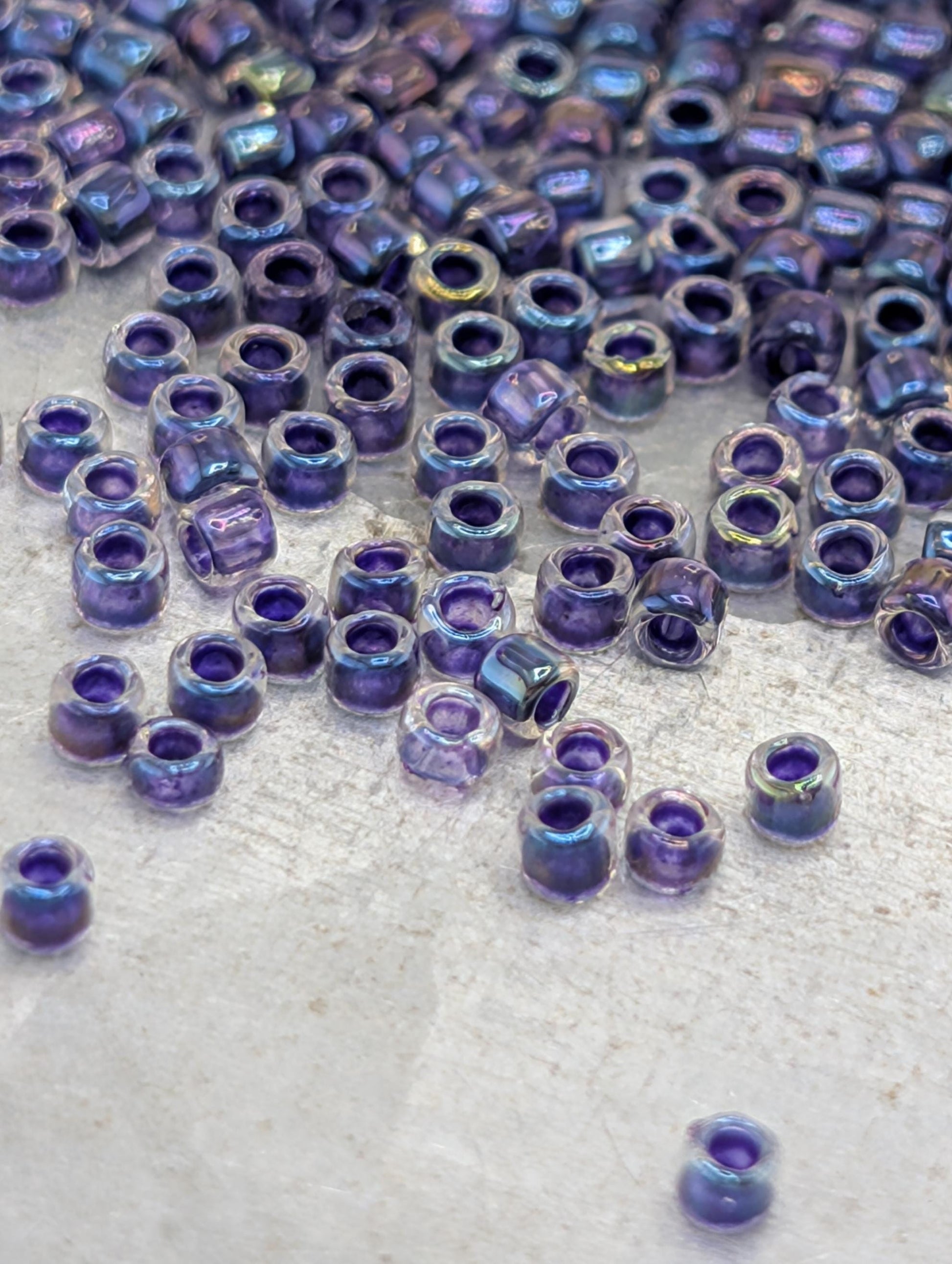 a collection of small, clear beads in various shades of purple scattered across a surface.