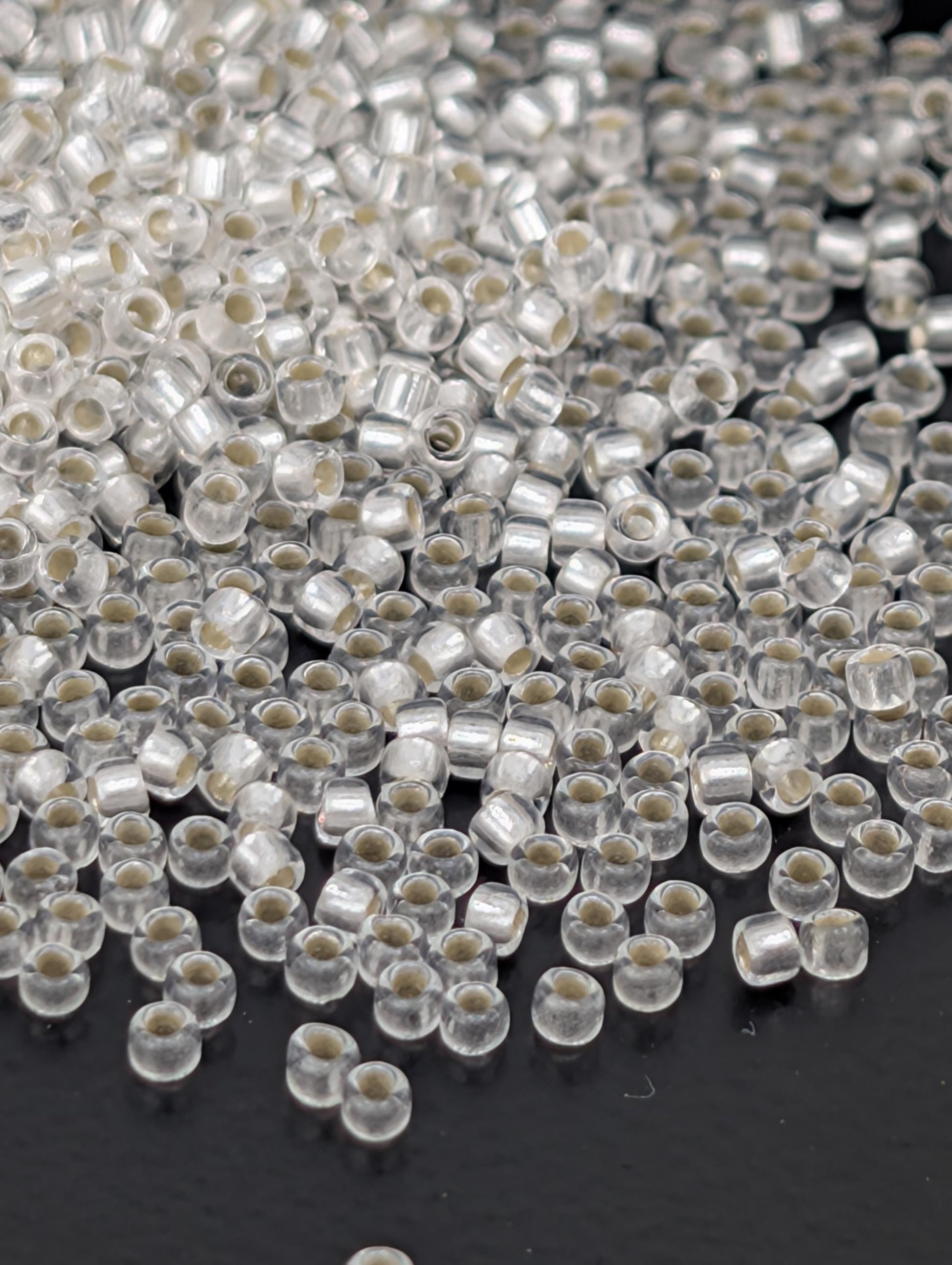 a close-up view of numerous clear beads scattered on a dark surface.