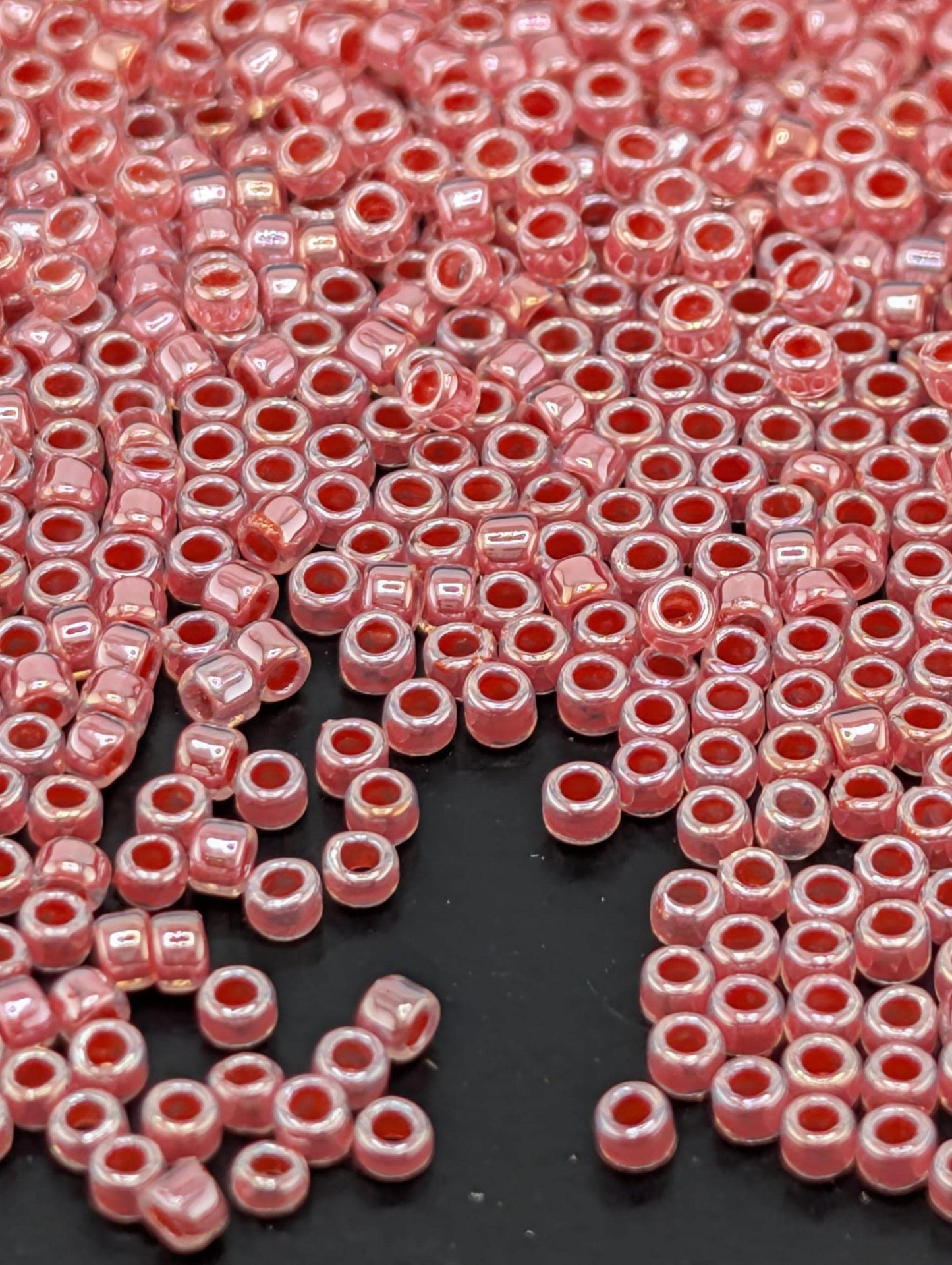 a close-up view of numerous small, round beads in a pink color, scattered across a dark background.