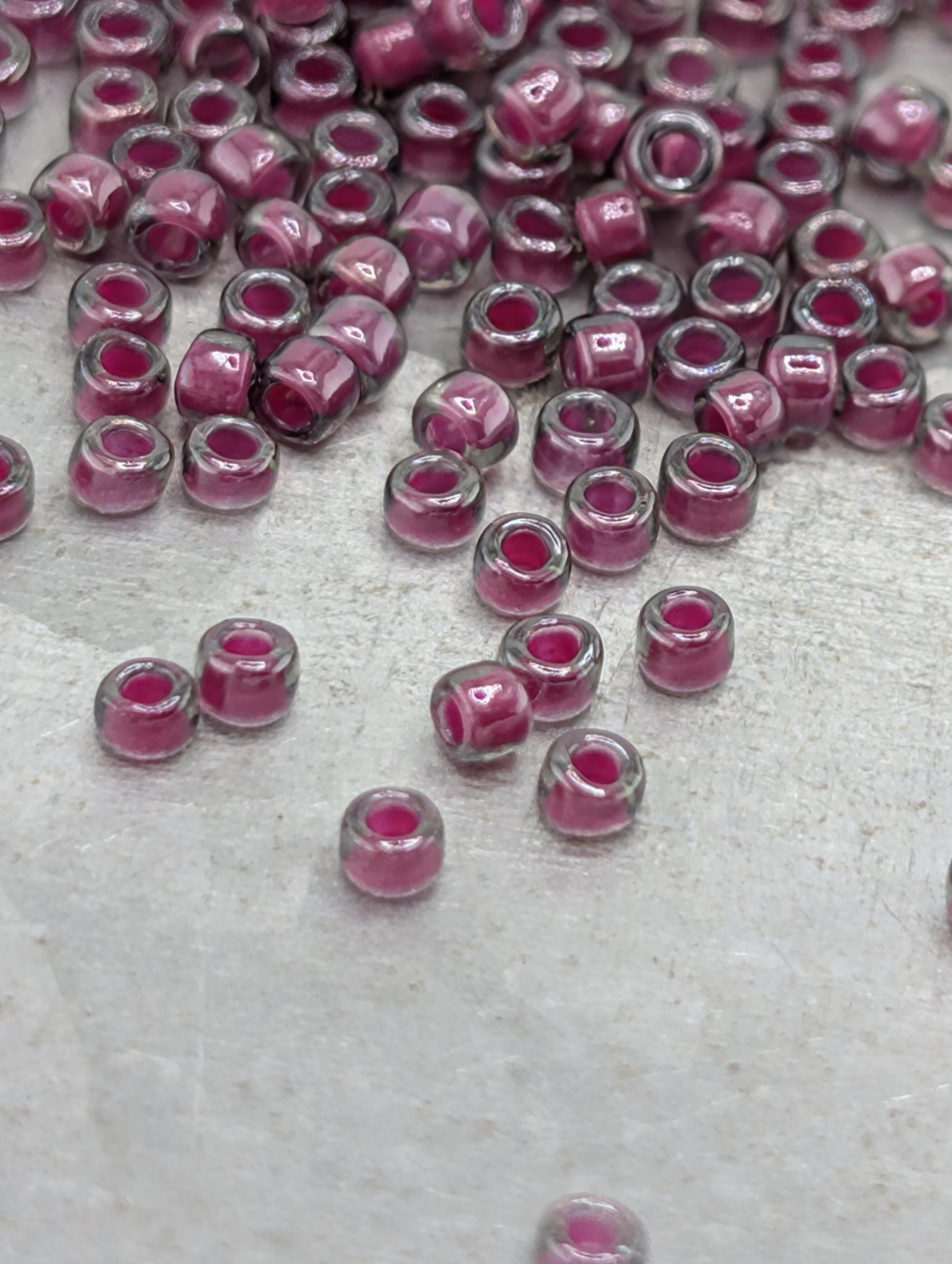 a collection of small, clear beads in shades of pink and purple, scattered across a surface.