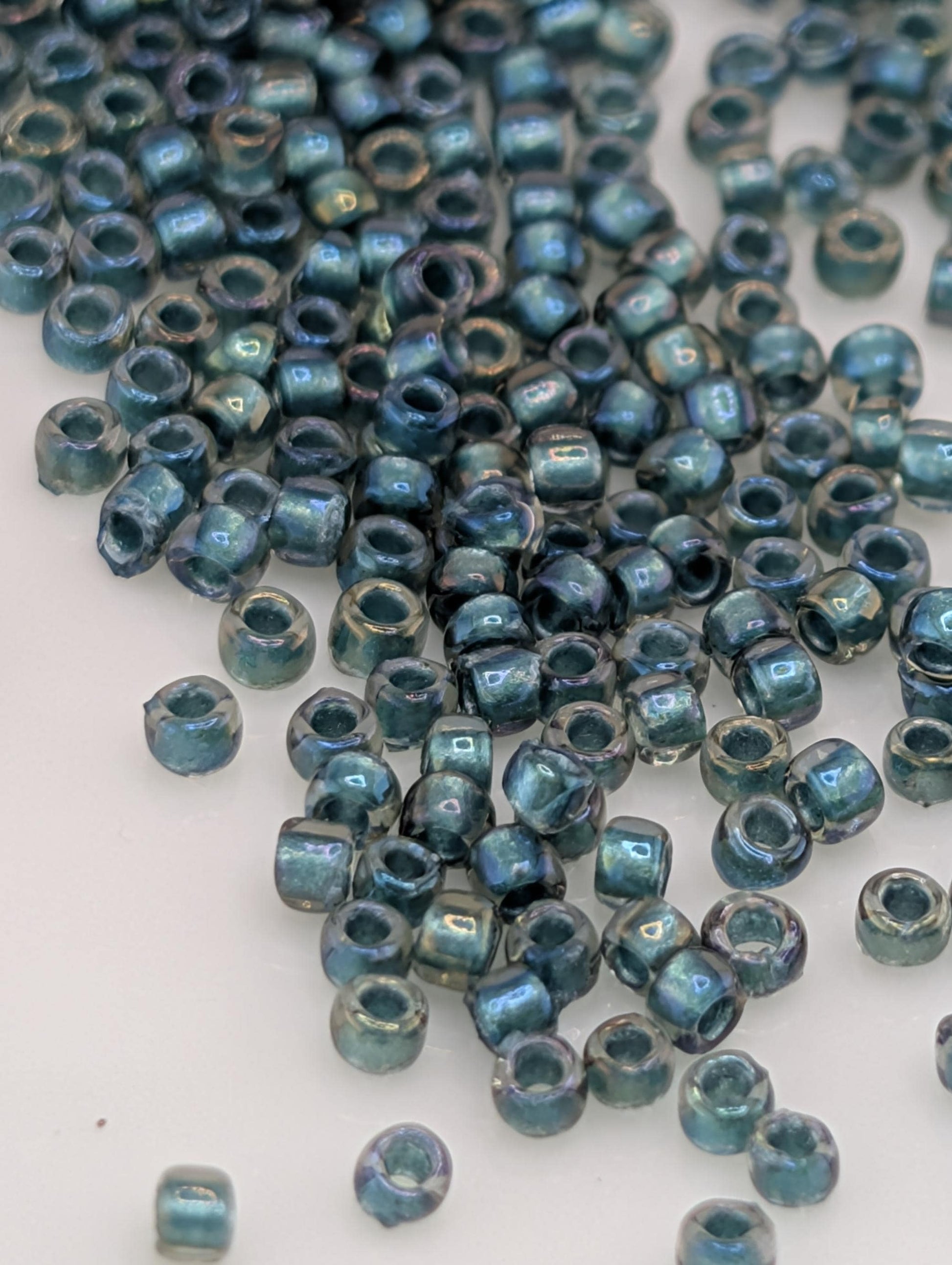 a collection of small, round beads in various shades of blue and green, scattered across a white surface.