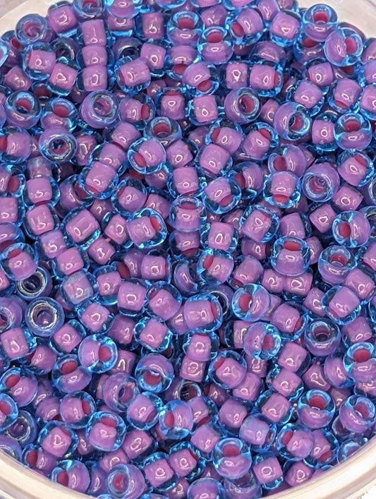 A close-up image of a collection of small, clear beads in various shades of purple and blue.