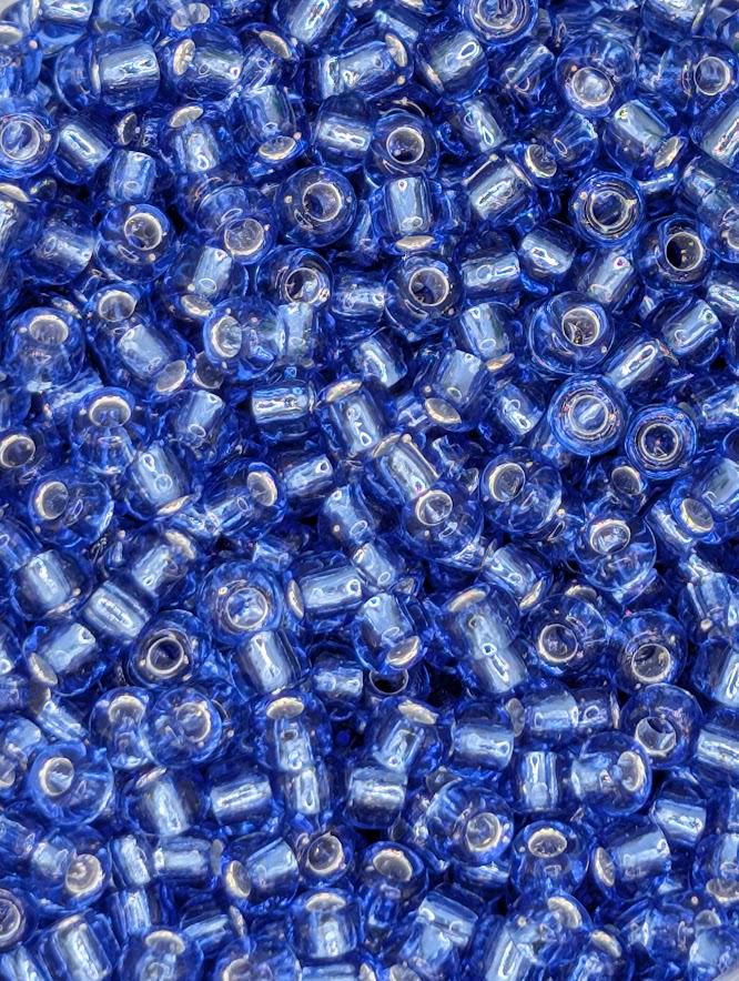 The image is a close-up of numerous blue glass beads or beads, arranged in a visually appealing manner.
