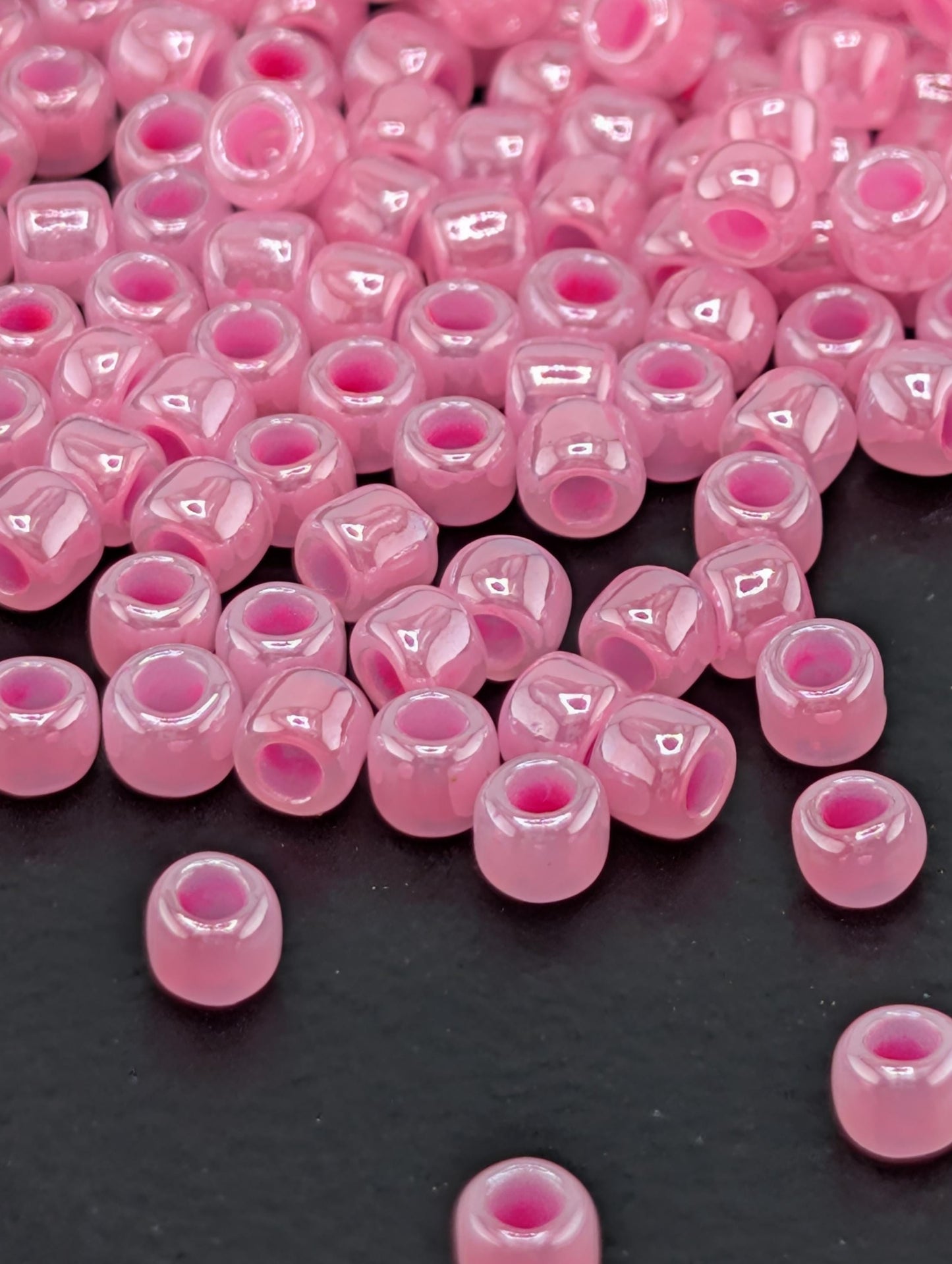a collection of small, round, pink beads scattered on a dark surface.