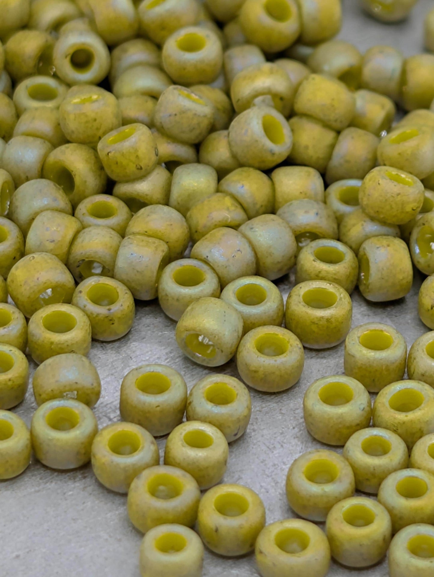 a collection of small, round beads in various shades of yellow, scattered across a surface.